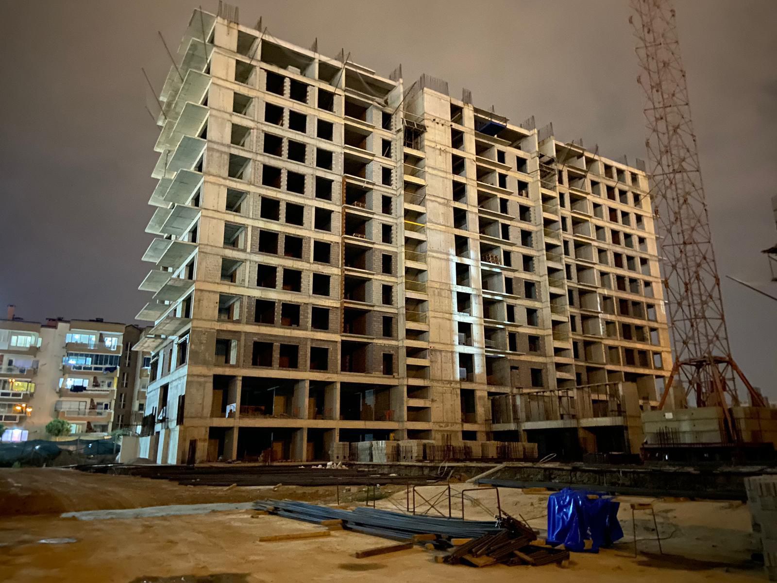 side view of smiling handsome electrician repairing electrical box with pliers in corridor